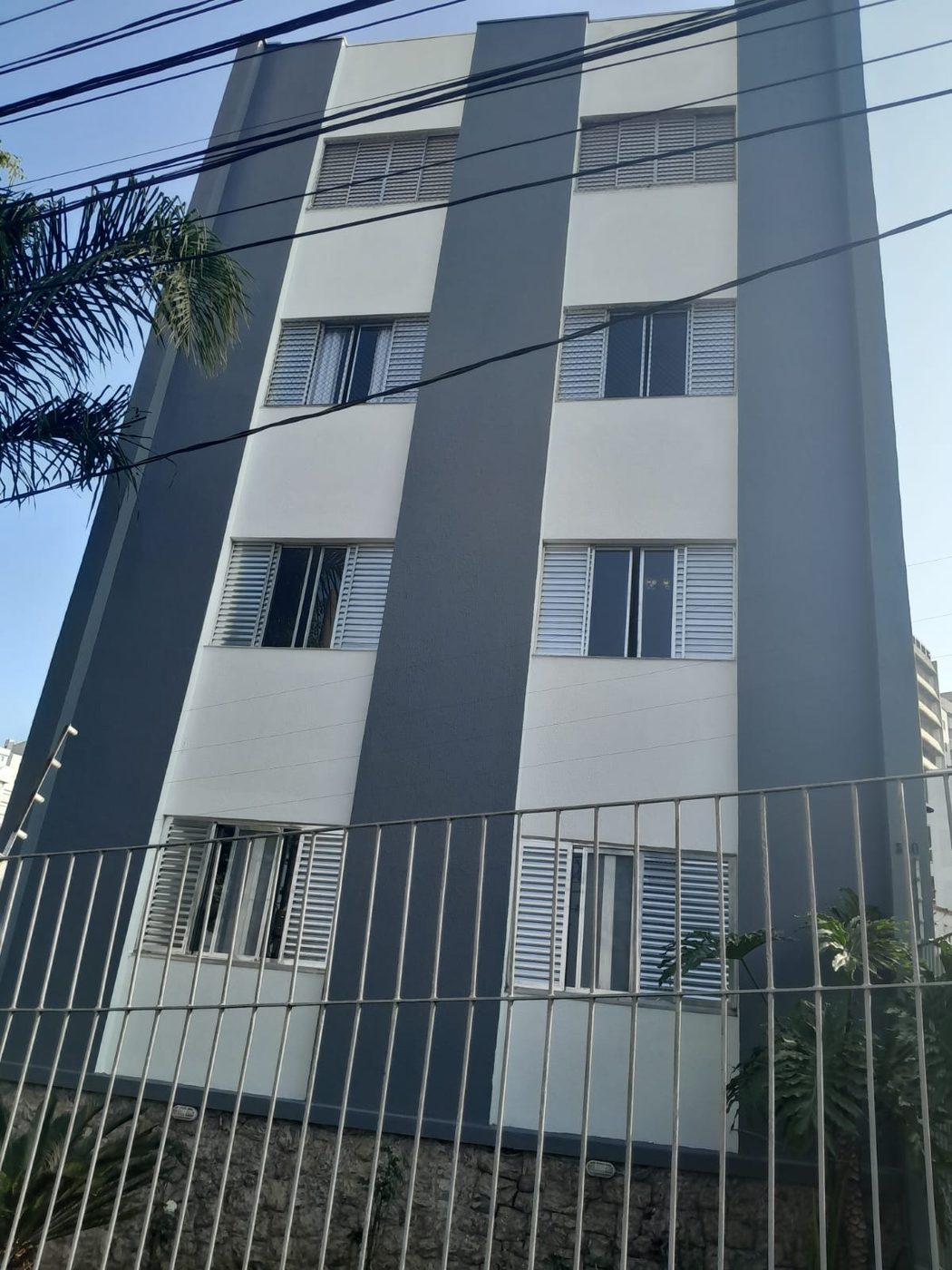 Fachada de prédio de quatro andares pintada em faixas de cinza e branco