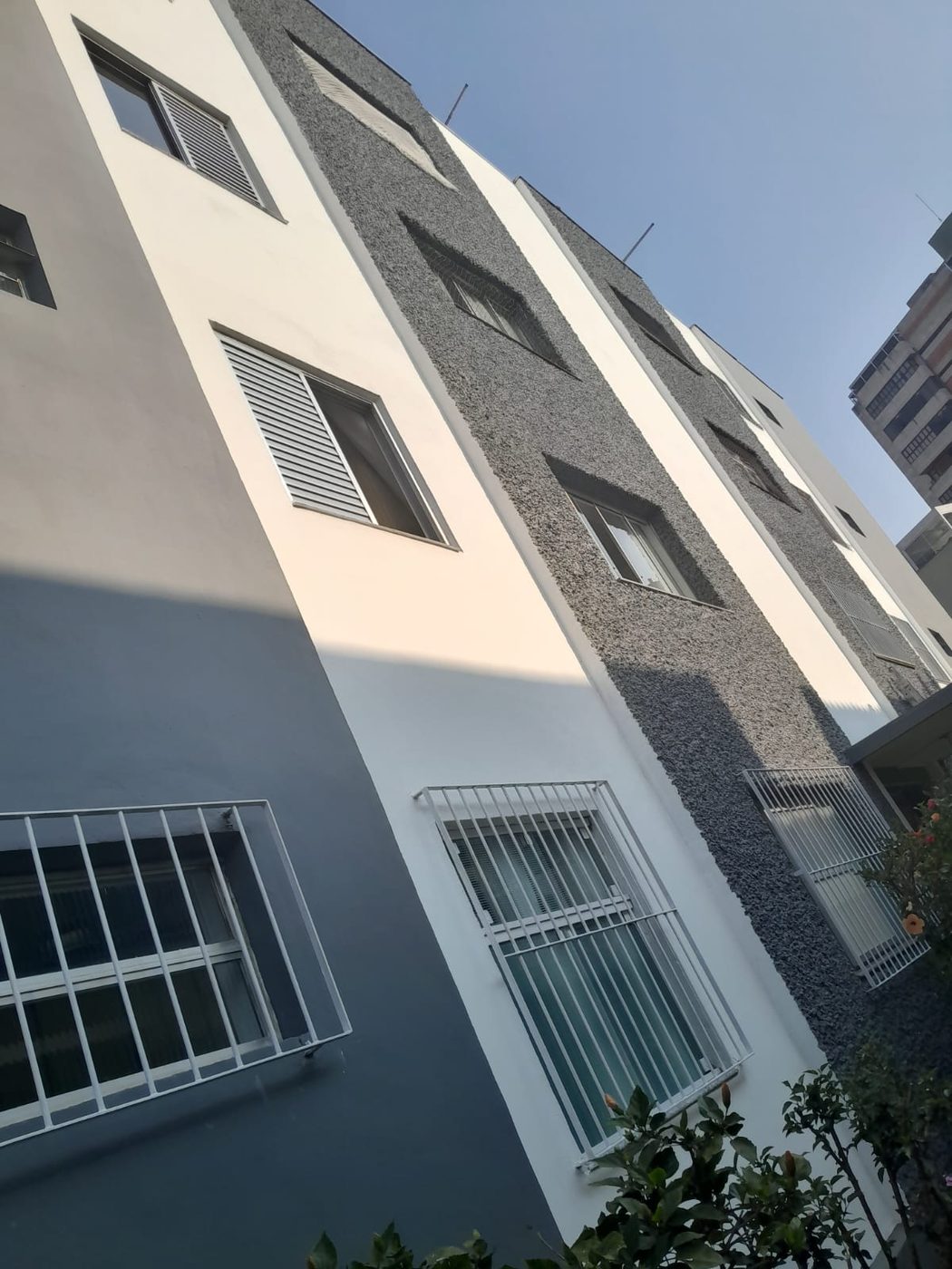 Lateral de prédio pintada em branco e cinza, com a textura da parede preservada