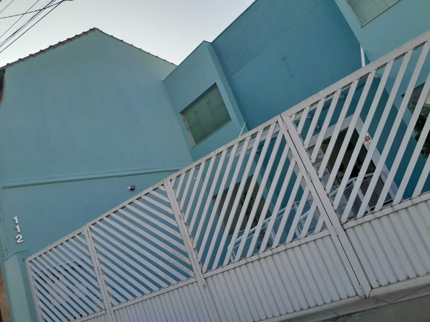 Acabamento da fachada de um sobrado pintado em azul claro, visto de baixo